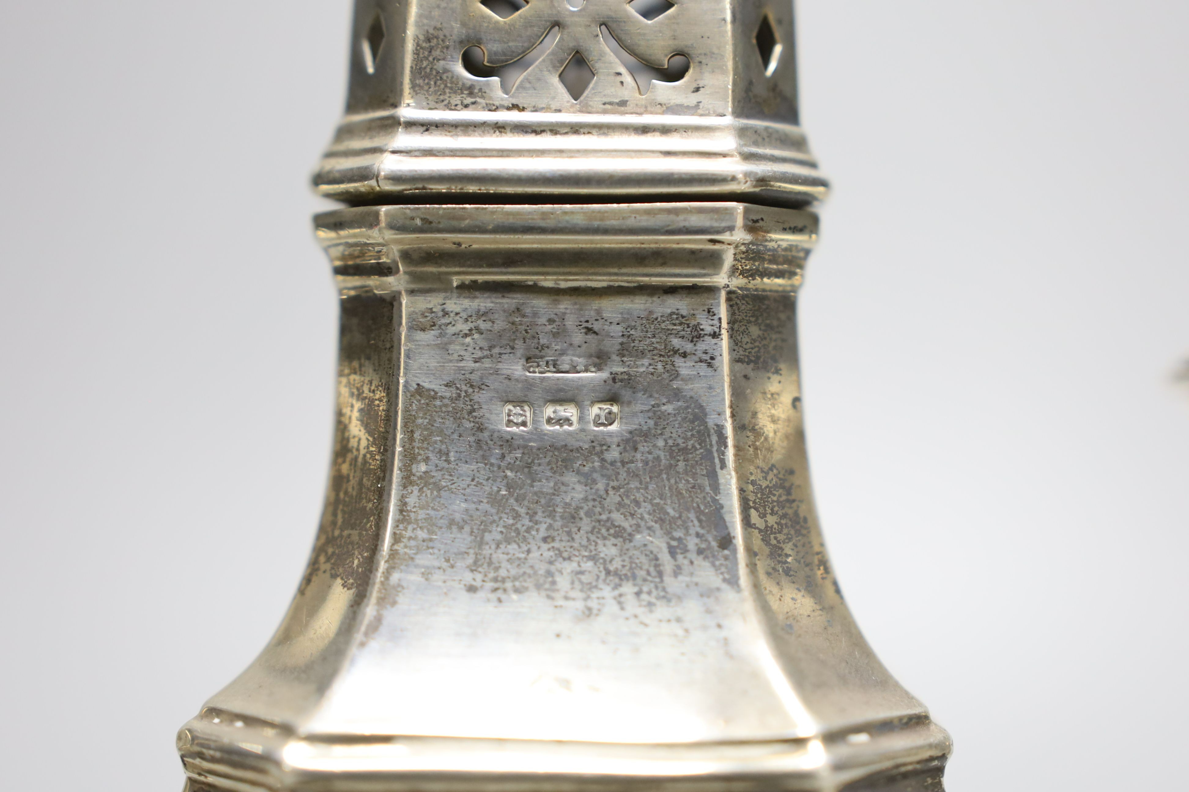 A modern pair of sterling mounted dwarf candlesticks, 92mm and a George V silver sugar caster, 16.5cm, 157 grams.